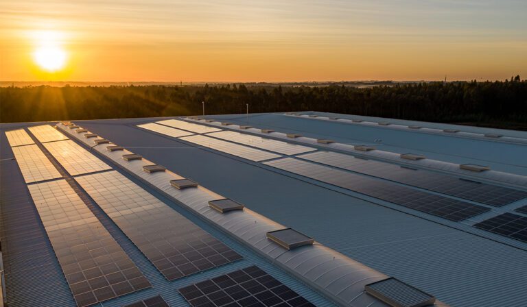 Solar PV array on a factory roof in front of a sunset