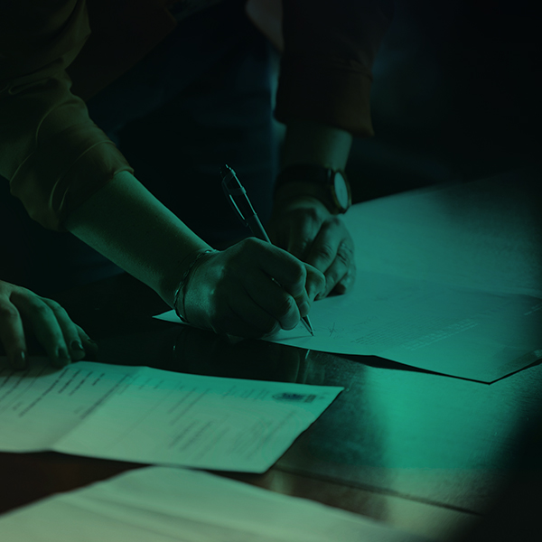 Woman signing a business contract on a wooden desk