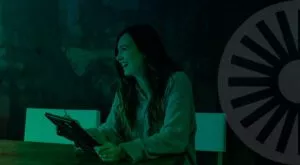 A woman at a TPI holding a tablet at a wooden table as she discusses business energy