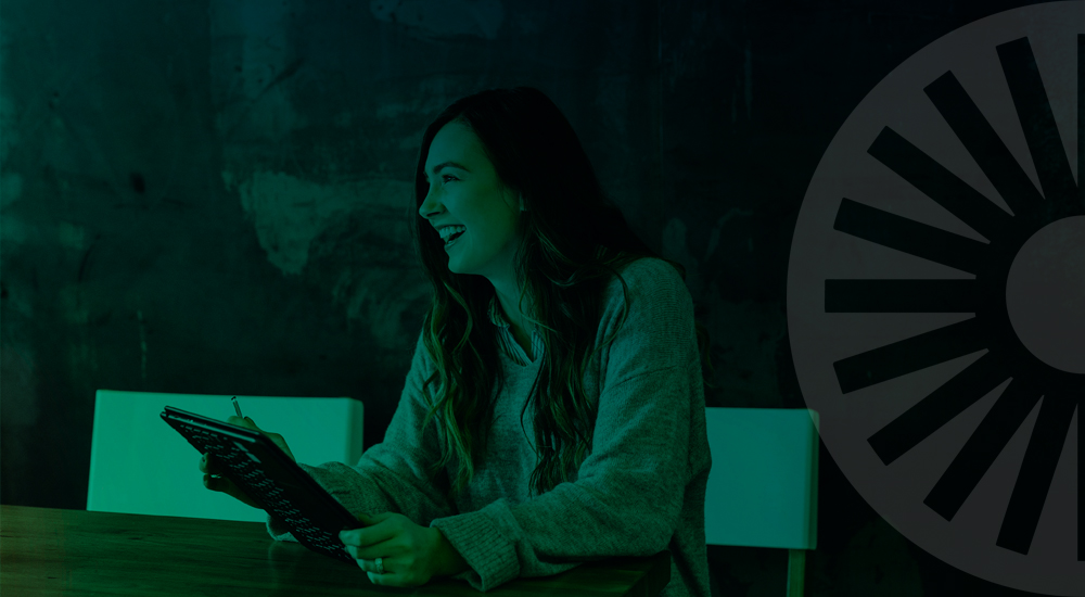 A woman at a TPI holding a tablet at a wooden table as she discusses business energy