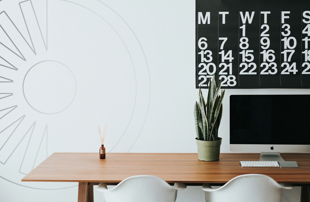 A computer and calendar rest on a wooden desk