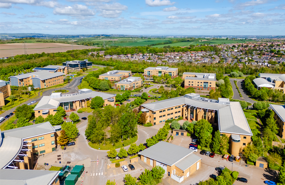 Aerial view of Doxford Works building on Doxfrod International Business Park, featuring other office buildings and trees and greenery.